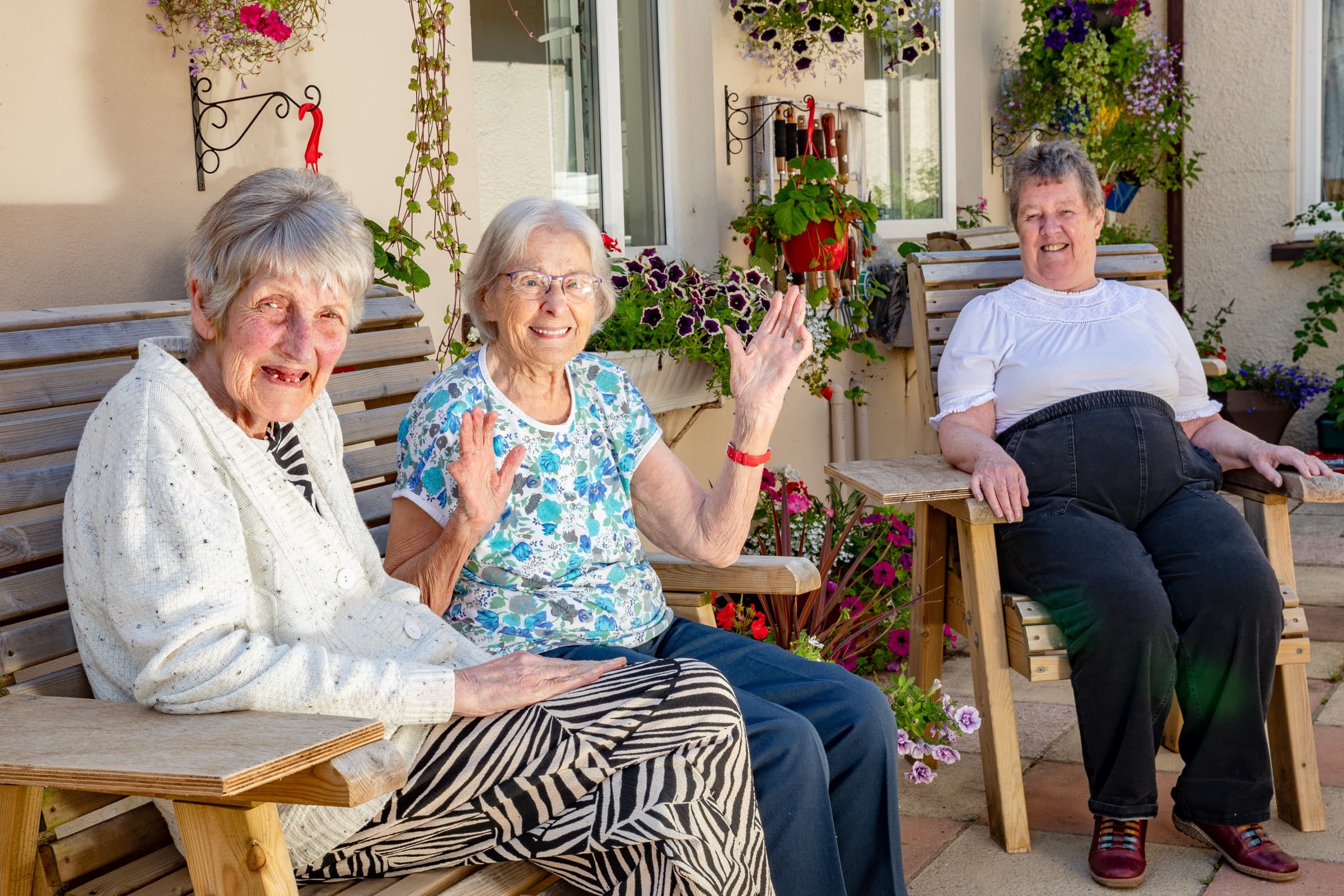 Residents relaxing together on benches in the flower-filled courtyard