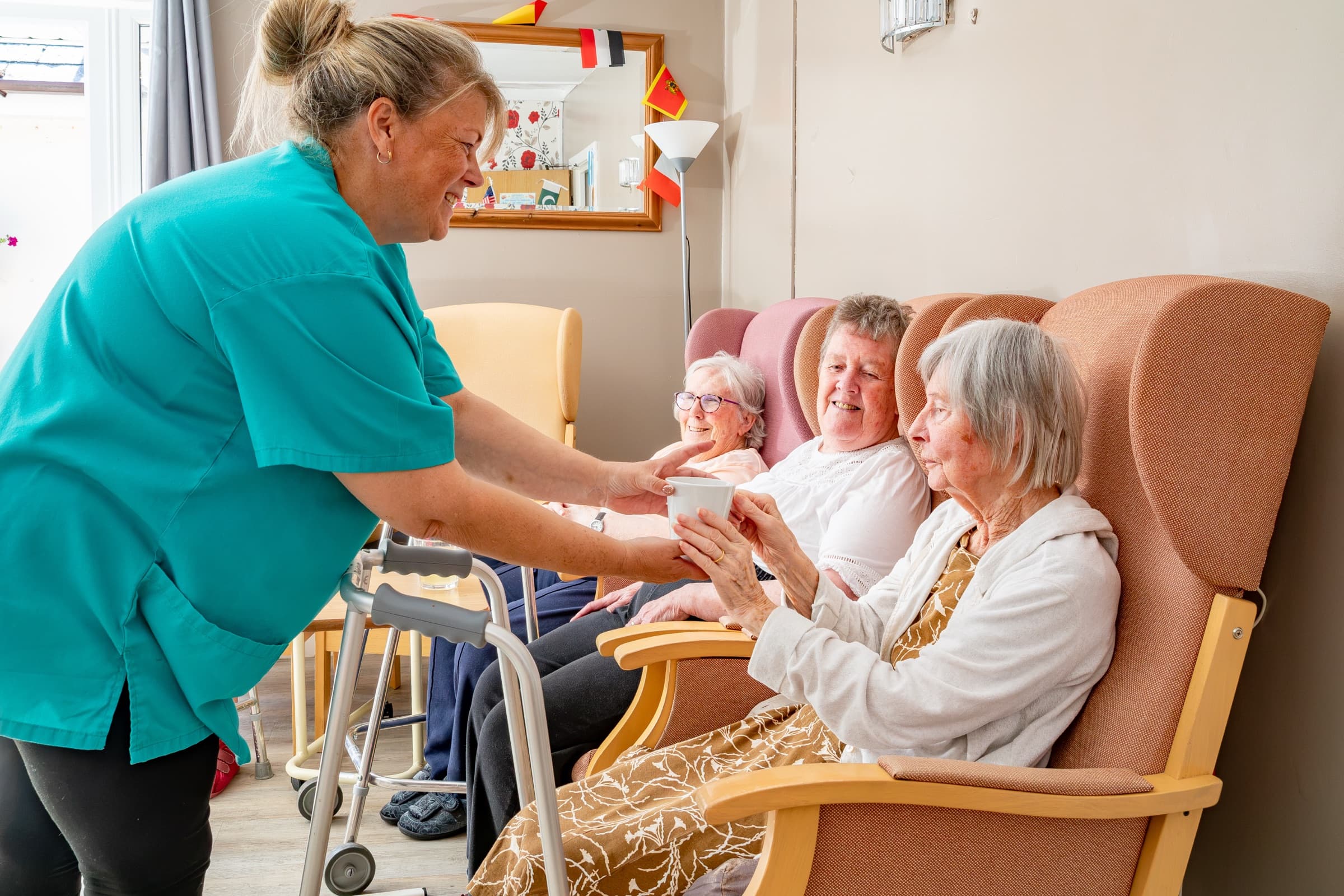 A member of staff serving drinks to residents in the lounge