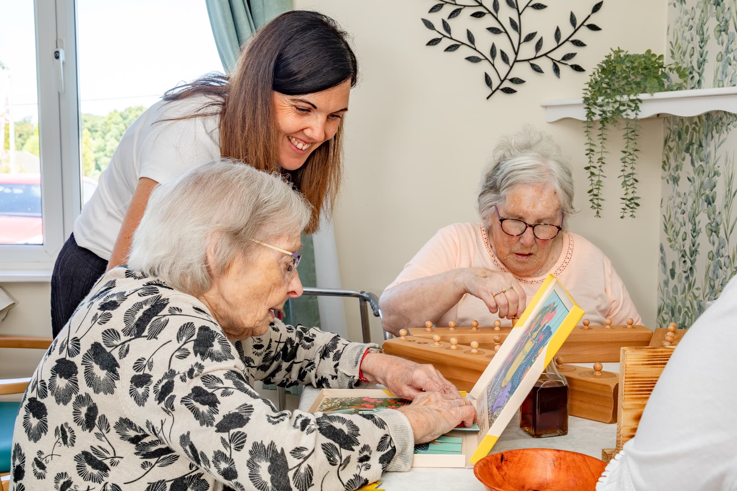 A member of staff and two residents using wooden Montessori materials at a table