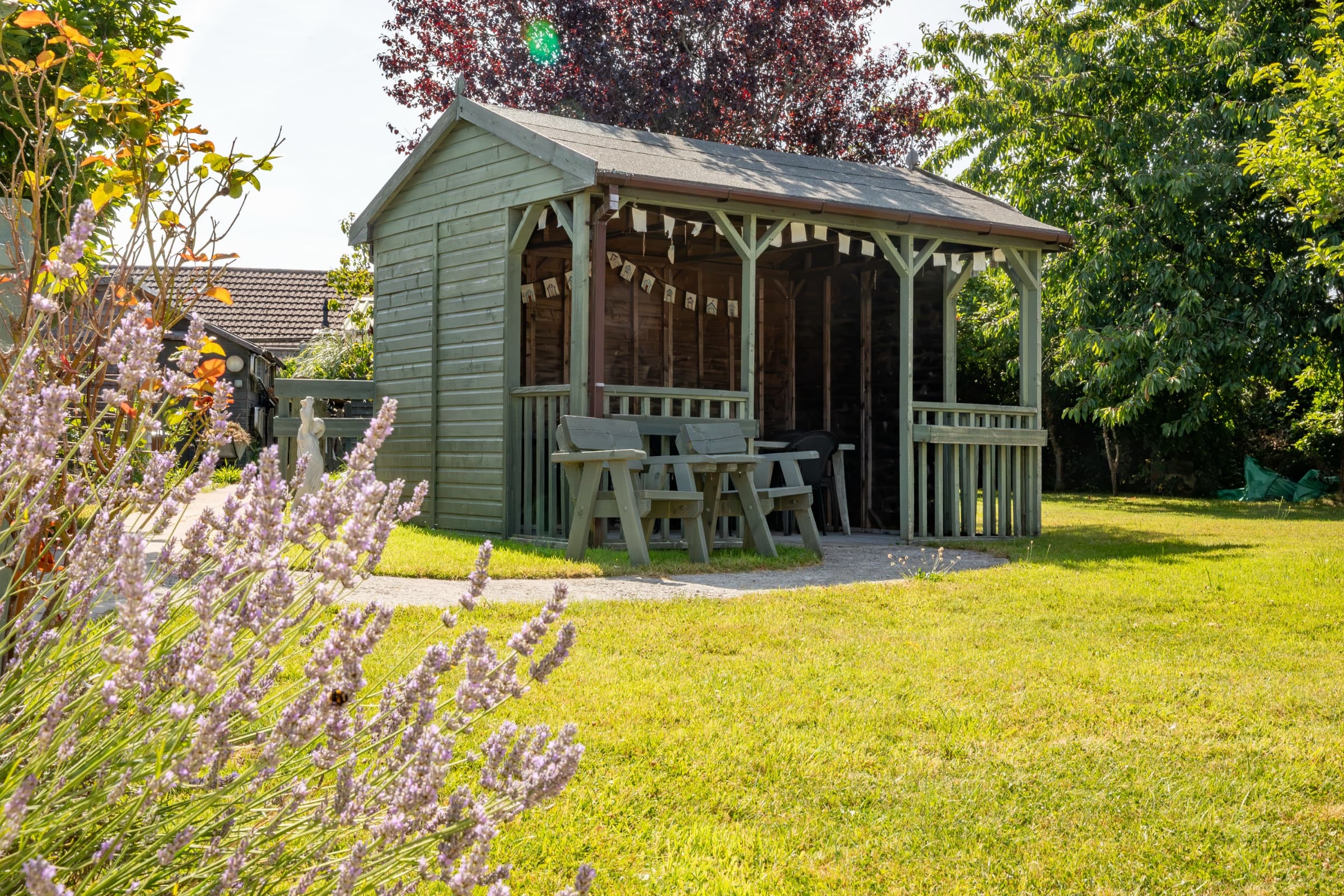 Garden shelter with seating, surrounded by lavender and lawn