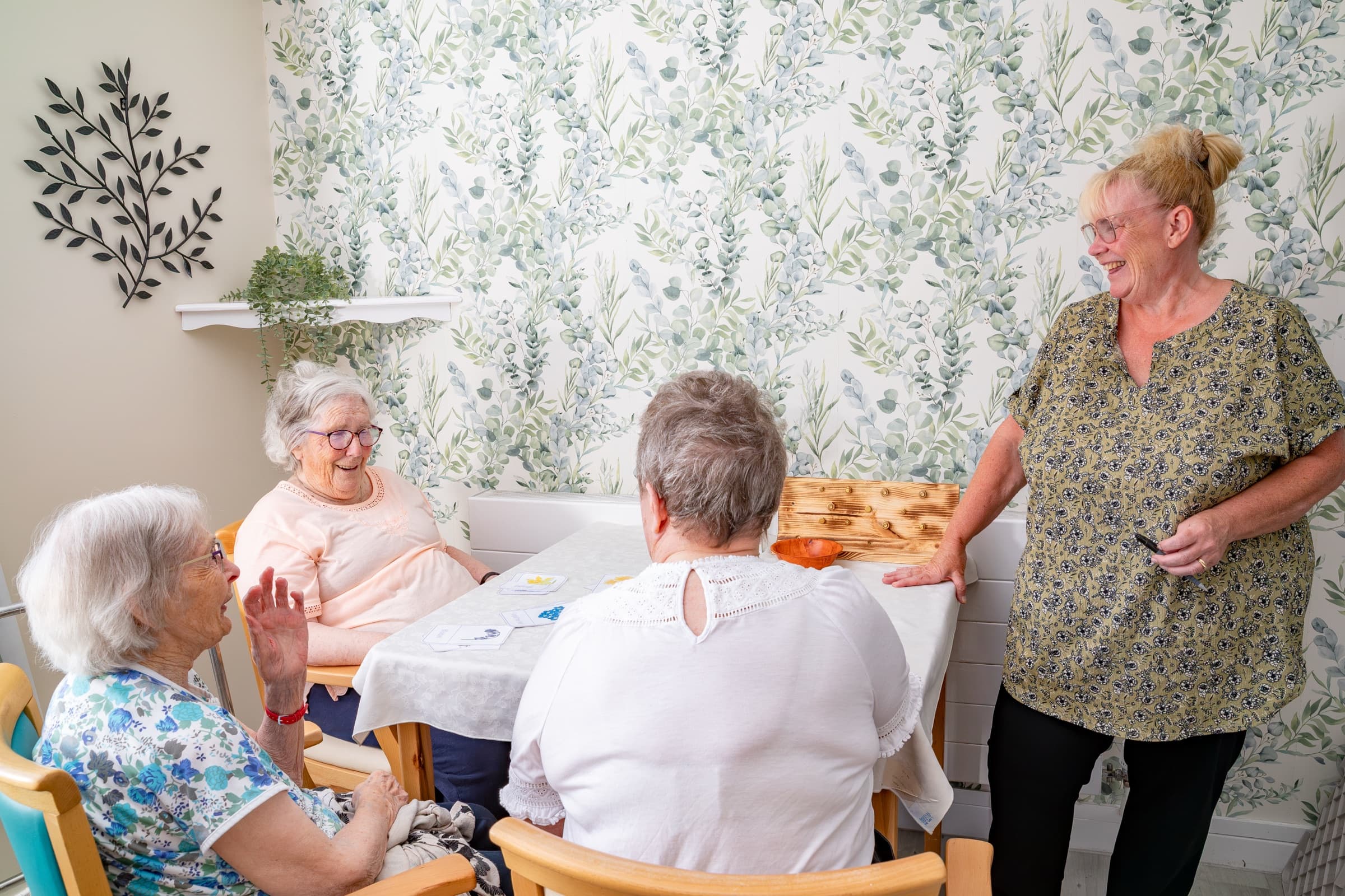 Residents chatting around a table with a member of staff