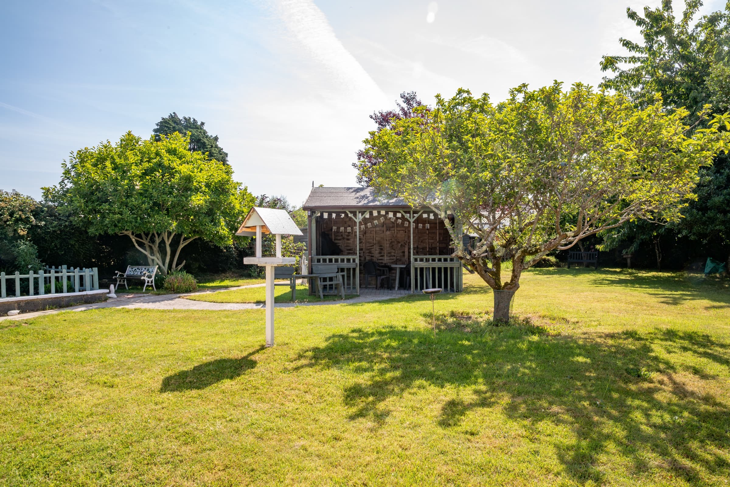 Lawned garden with a covered shelter and mature trees